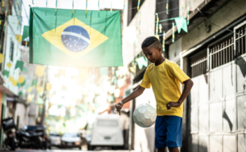 Quando a publicidade brasileira entendeu que o Brasil era a referência Rua decorada com bandeira do Brasil e menino jogando bola.