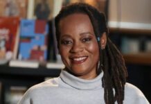 Eliana Alves Cruz vence prêmio da ABL de Melhor Livro de Ficção com ‘Meridiana’ Escritora Eliana Alves Cruz sorrindo com um cenário de livros atrás.