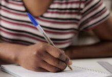 Educação básica e raça: Onde estamos e o que falta para alcançar a verdadeira equidade? Estudante negra escrevendo no caderno com uma caneta.