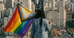 Mulher negra trans segurando uma bandeira LGBTPIAPN+.