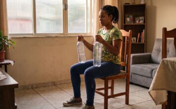 Por que a mulher negra precisa de musculação mesmo trabalhando o dia inteiro? Mulher negra fazendo musculação em casa